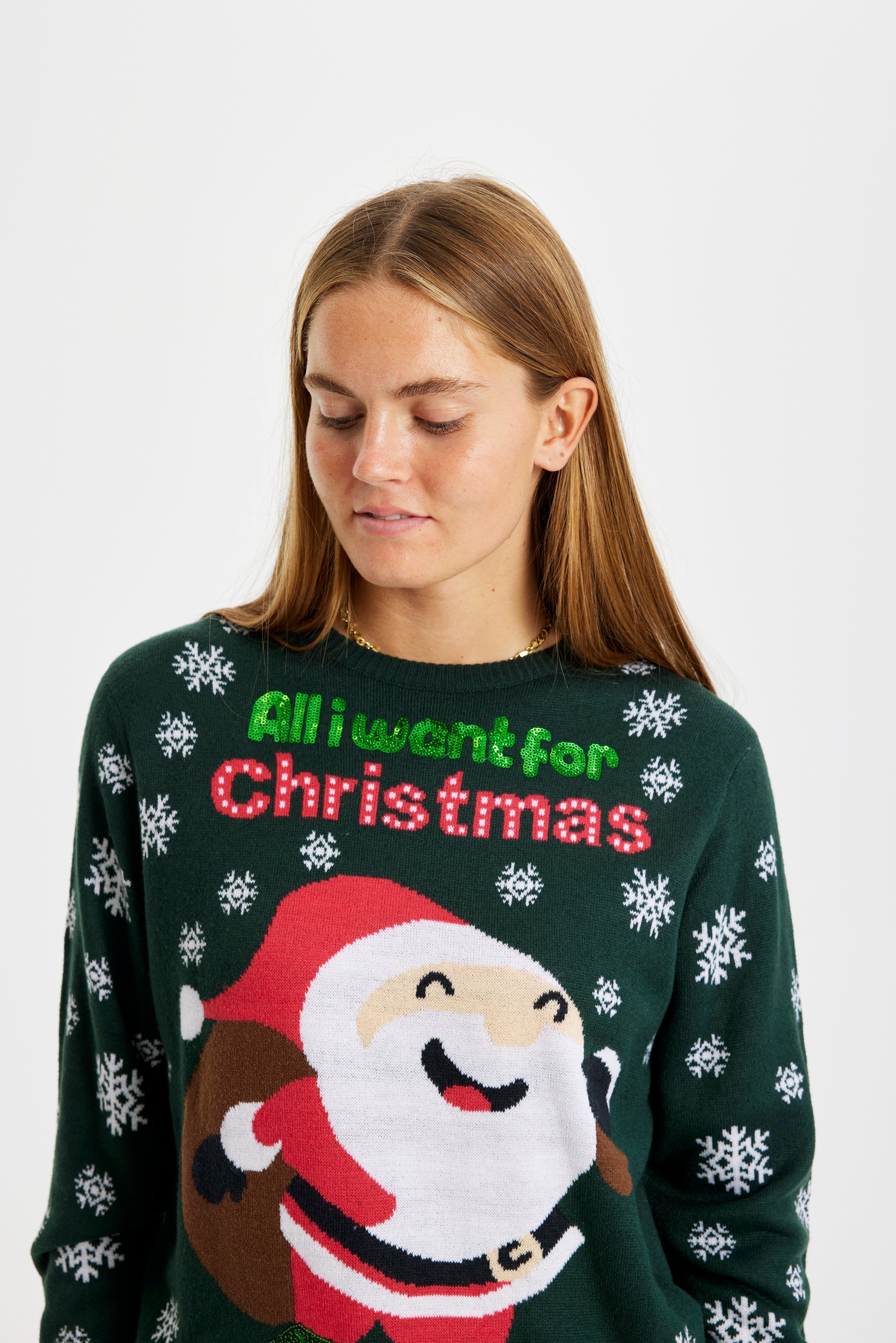 Et billede af en dame fra torsoen og op, som er iført en julesweater med snefnug og en glad julemand med en gavesæk.